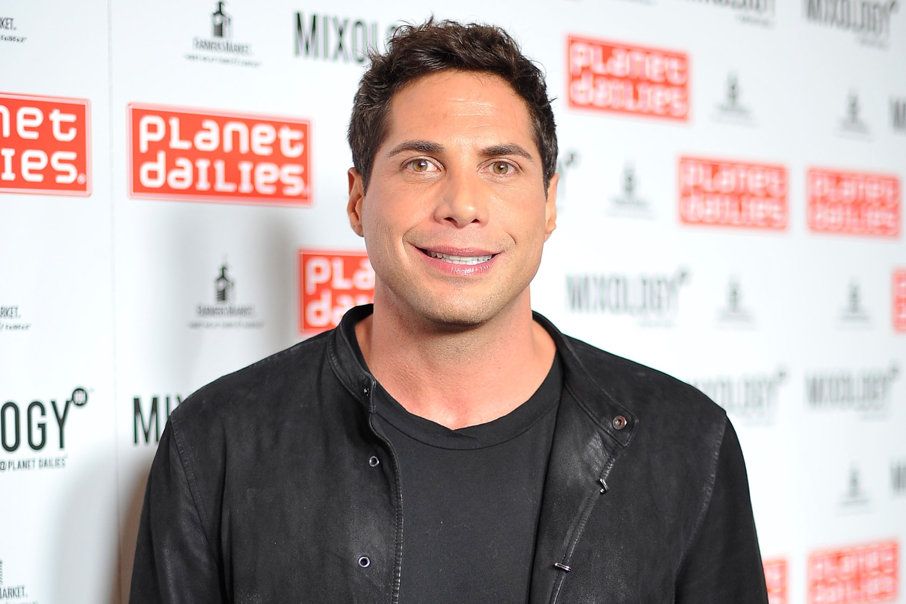 Joe Francis smiles on the red carpet in a leather jacket