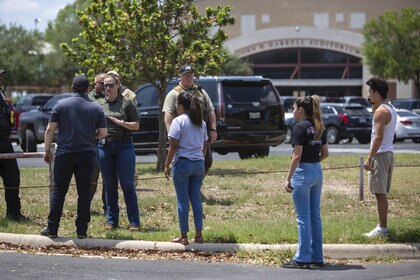 A law enforcement officer speaks with people outside Uvalde High School