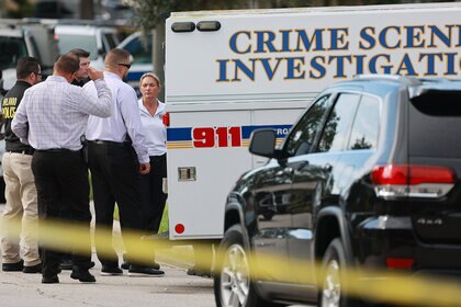 Officers and investigators gather in front of a home on Lake District Lane