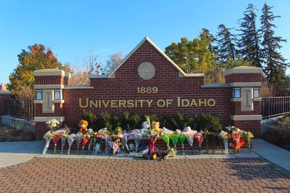 Flowers and stuffed animals are lined up outside a sign along Pullman Road in Moscow, Idaho