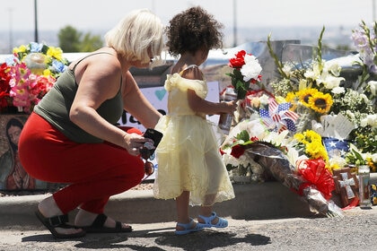 People are seen leaving flowers and a candle outside Walmart