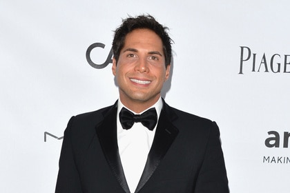 Joe Francis wearing a tuxedo on a step and repeat