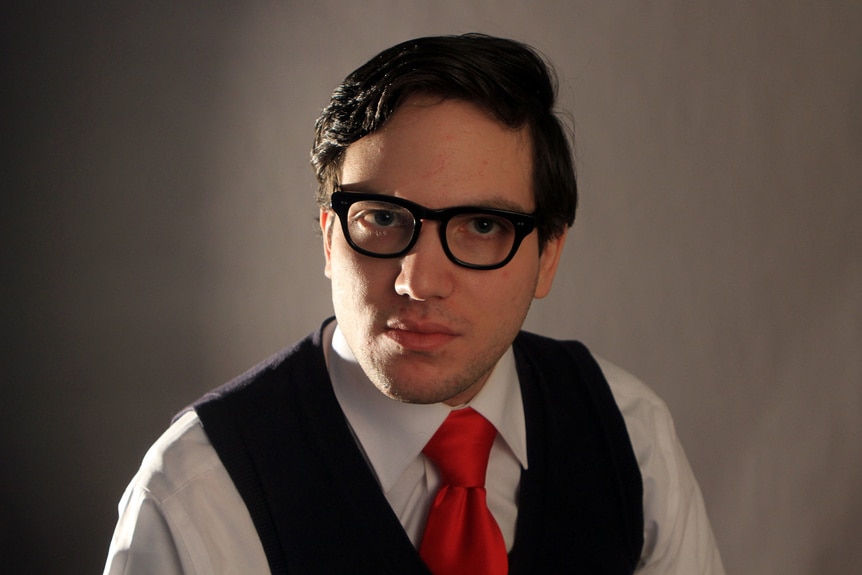 Nick Rossi wears glasses and a red tie